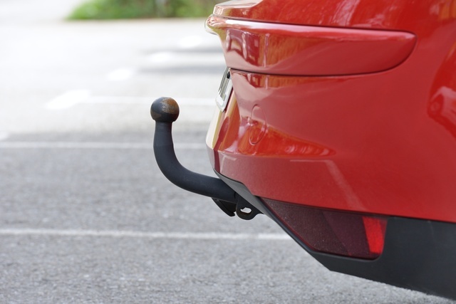 An einem roten Auto ist eine Anhängerkupplung mit Kugelkopf montiert, ideal zum Ziehen von Anhängern oder Wohnwagen.